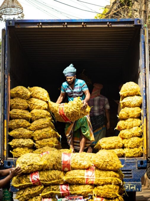 Laborers loading sacks into a truck, showcasing vibrant street market scene.